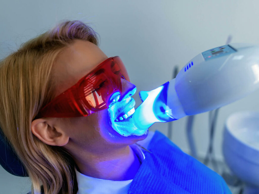 A woman receiving ultra violet light enhanced teeth whitening